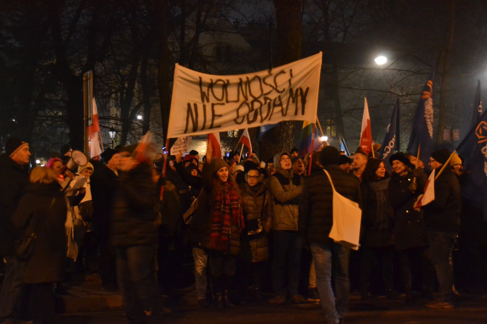 Pro-democracy demonstration in Poland, with protesters carrying Polish flags and a banner reading ‘Wolności nie oddamy’